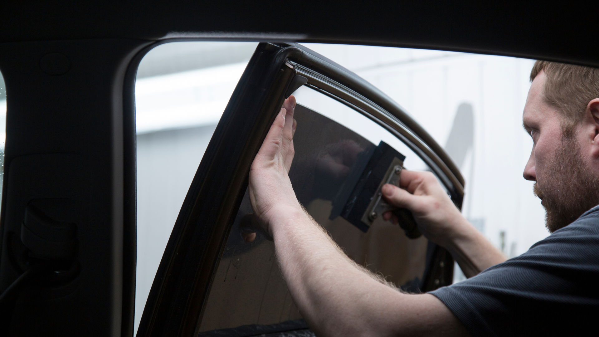 Installer squeegeeing SunTek window film onto a car door window